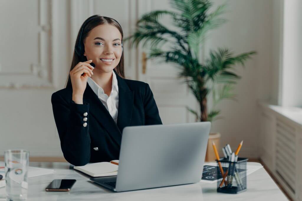 female office worker in headset smiling at camera during online meeting 1024x682 - 55 Ways To Use A Virtual Assistant